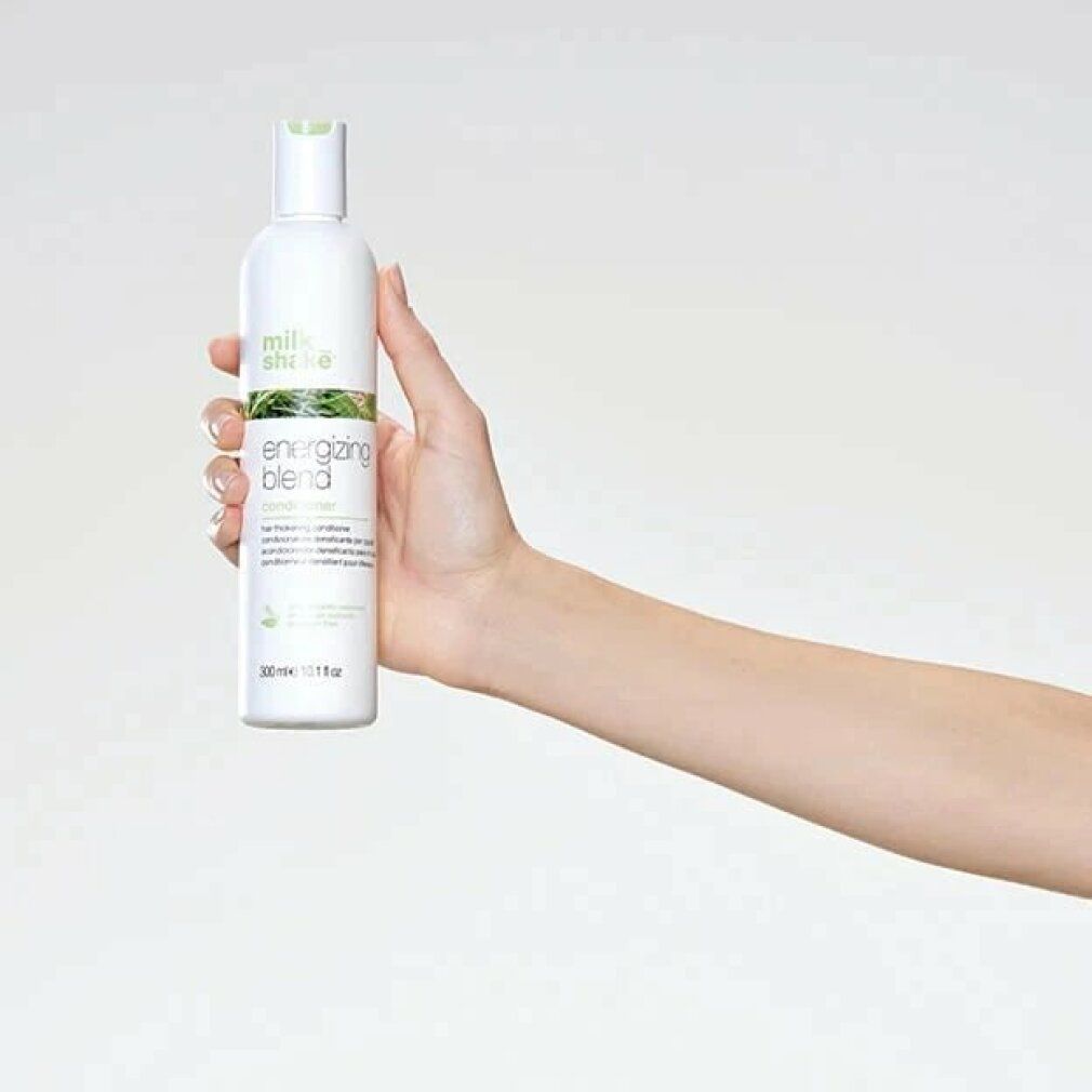 Wit product, vastgehouden door een hand. Opschrift: milk_shake Energizing Blend. Groen-witte verpakking. Fles met klapdeksel.