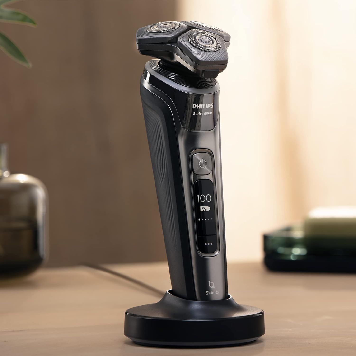 Rasoir électrique sur station de charge. Base noire, rasoir gris avec écran. Logo SkinIQ.
