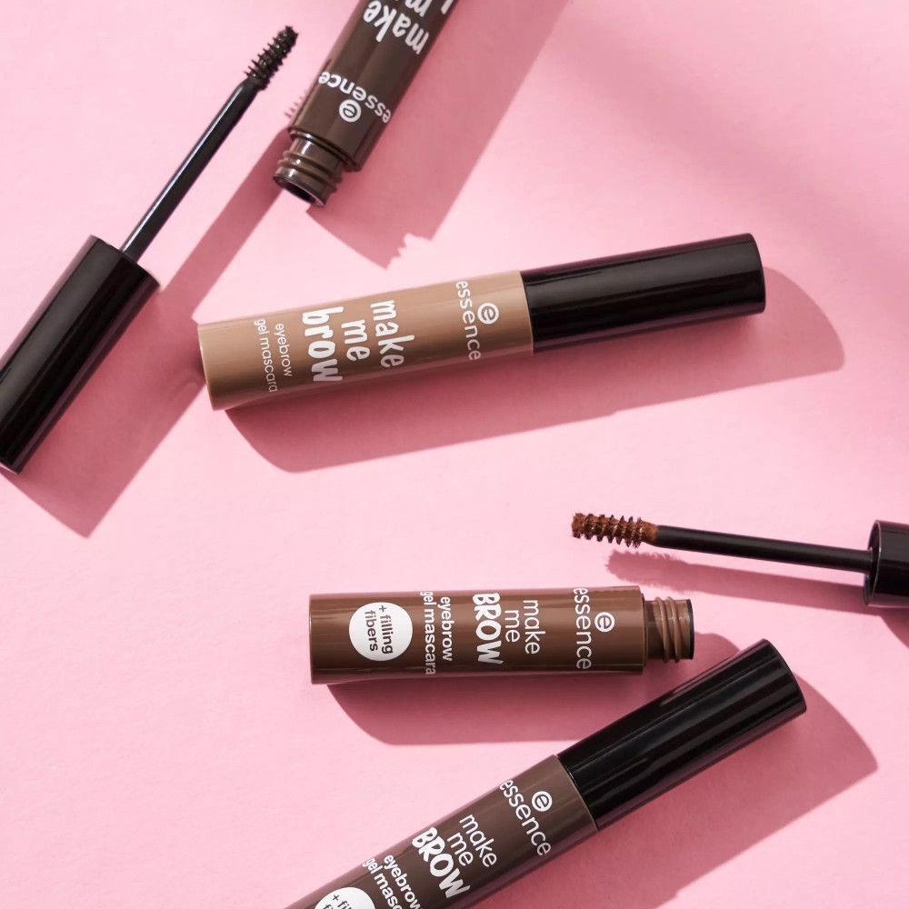 Wenkbrauwgel mascara tubes en borstels op roze achtergrond. Opschrift: make me brow, eyebrow gel mascara, + filling fibers.