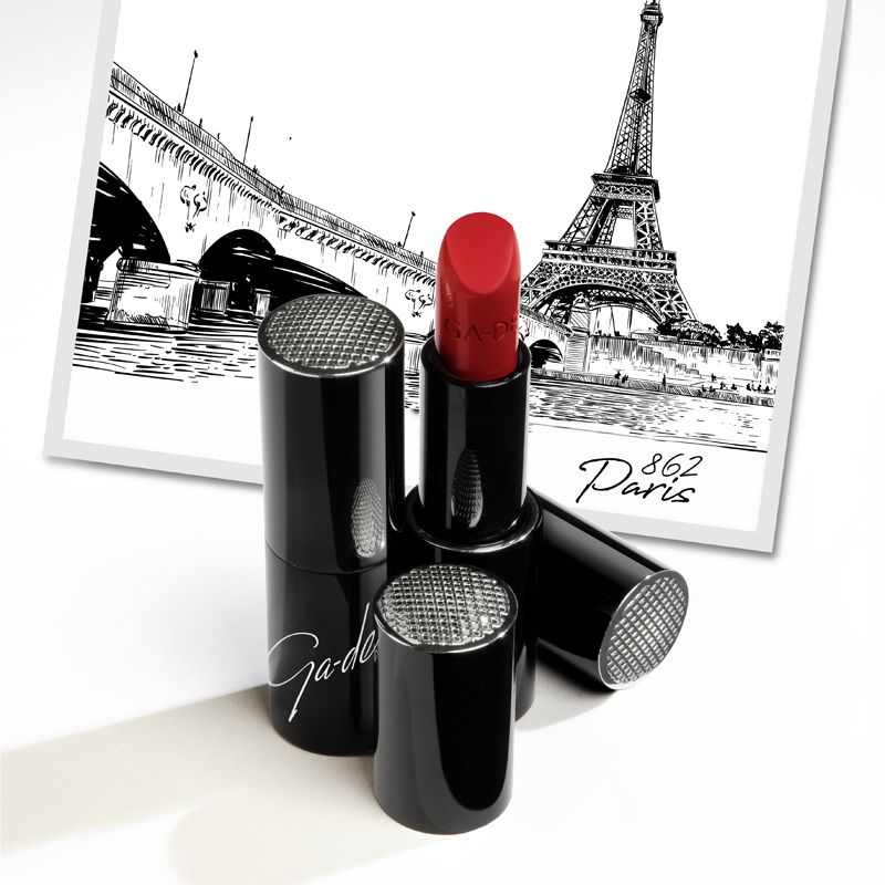 Rouge à lèvres rouge ouvert. Étuis noirs avec capuchons argentés. Logo Ga-De. Fond : illustration de Paris.