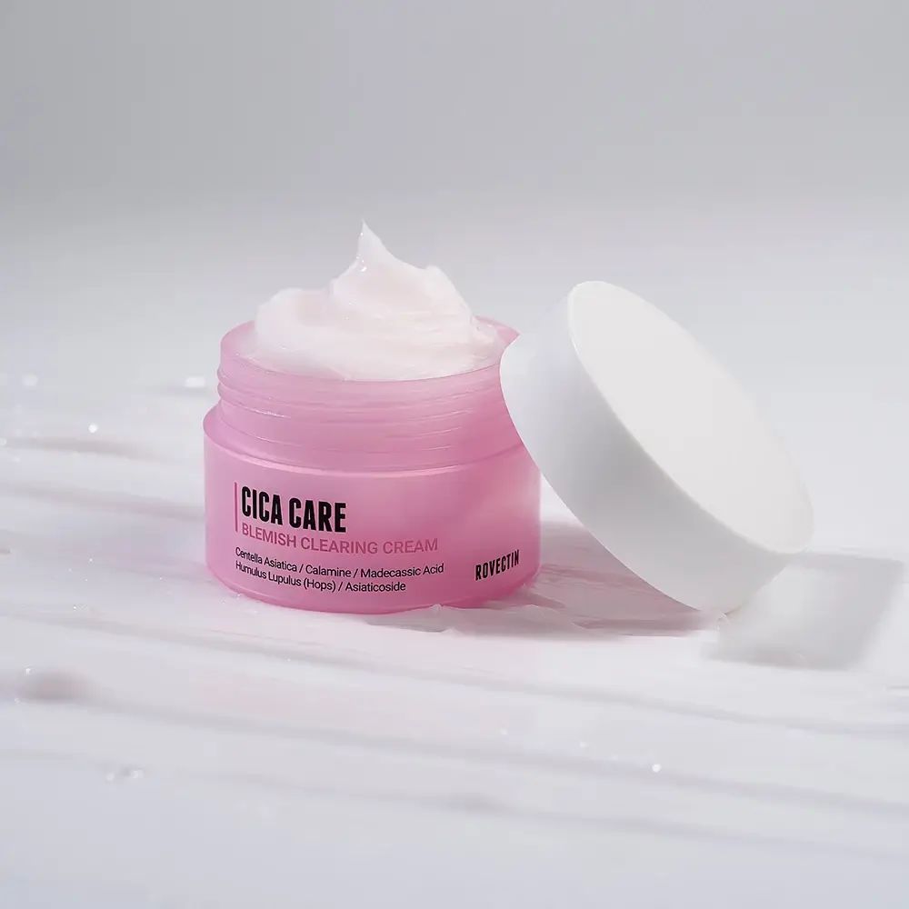 Open roze crèmepot met witte deksel. Crème zichtbaar. Opschrift: Cica Care Blemish Clearing Cream. Merk: Rovectin.