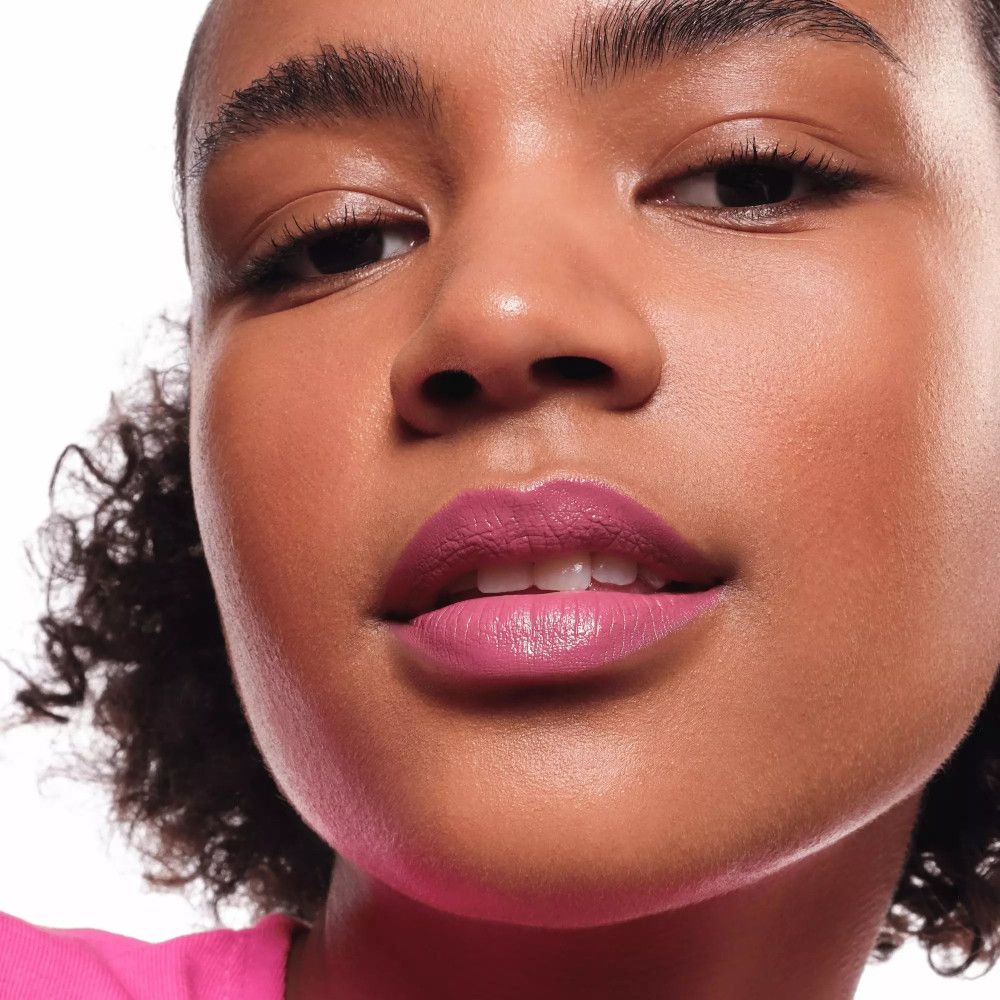 Gros plan sur une femme avec du rouge à lèvres rose. Elle a la peau foncée et les cheveux bouclés.