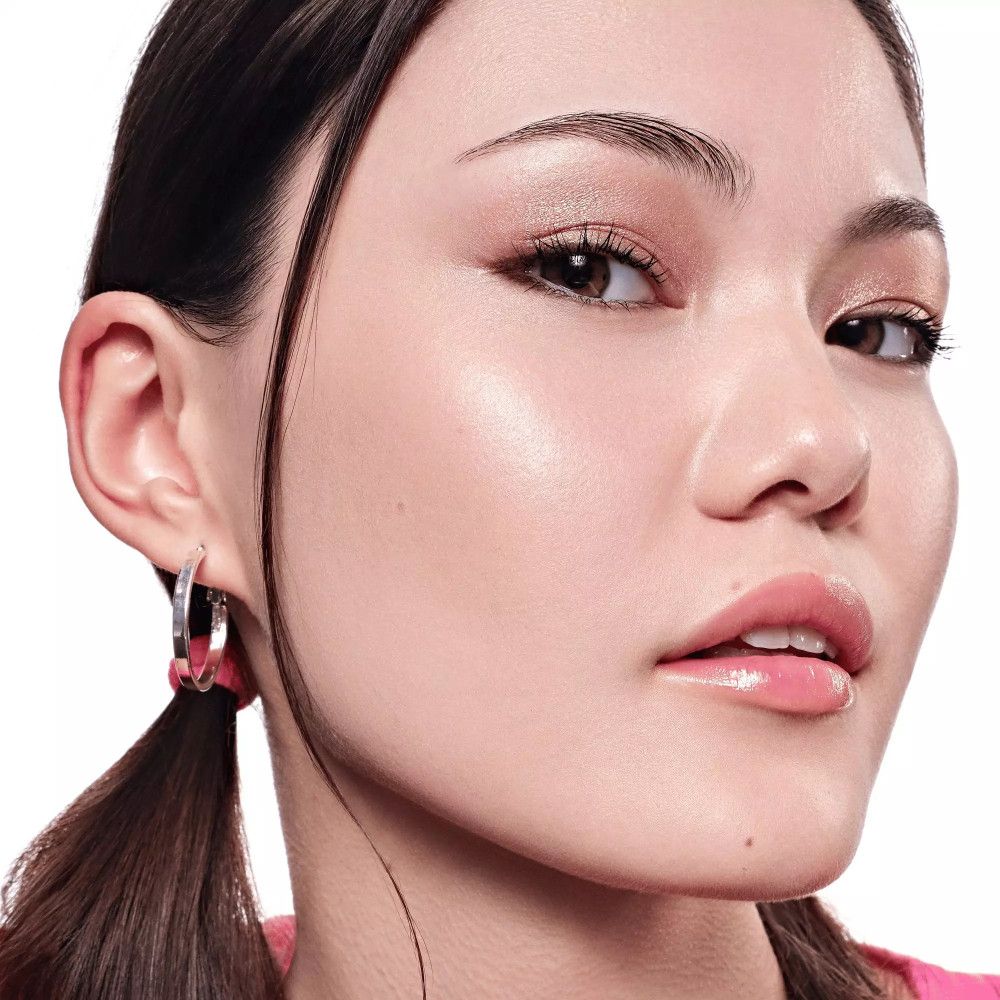 Portrait d'une femme au teint clair. Elle porte du fard à paupières et du rouge à lèvres. Sur fond blanc.