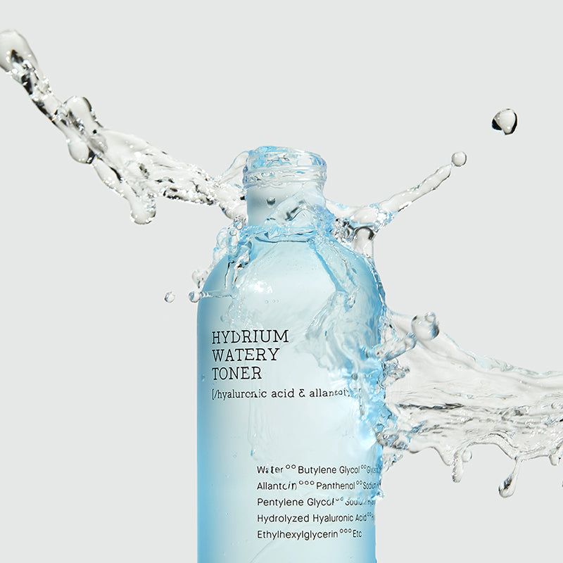 Blauw-transparante tonerfles met waterspetters. Opschrift: Hydrium Watery Toner. Ingrediënten zichtbaar.