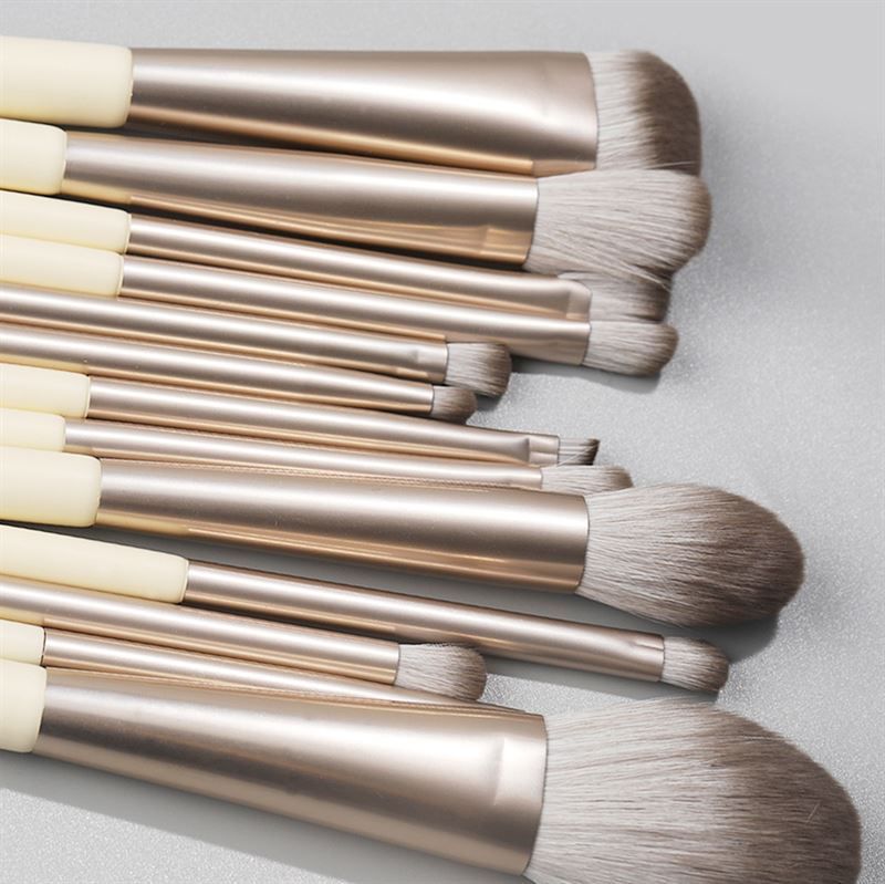 Gros plan sur des pinceaux de maquillage. Manches crème, viroles argentées et différentes têtes.