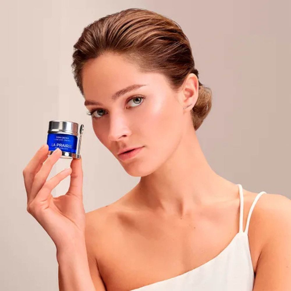 Vrouw houdt blauwe pot met zilveren deksel vast. Opschrift: Skin Caviar Luxe Eye Cream, La Prairie, Switzerland.