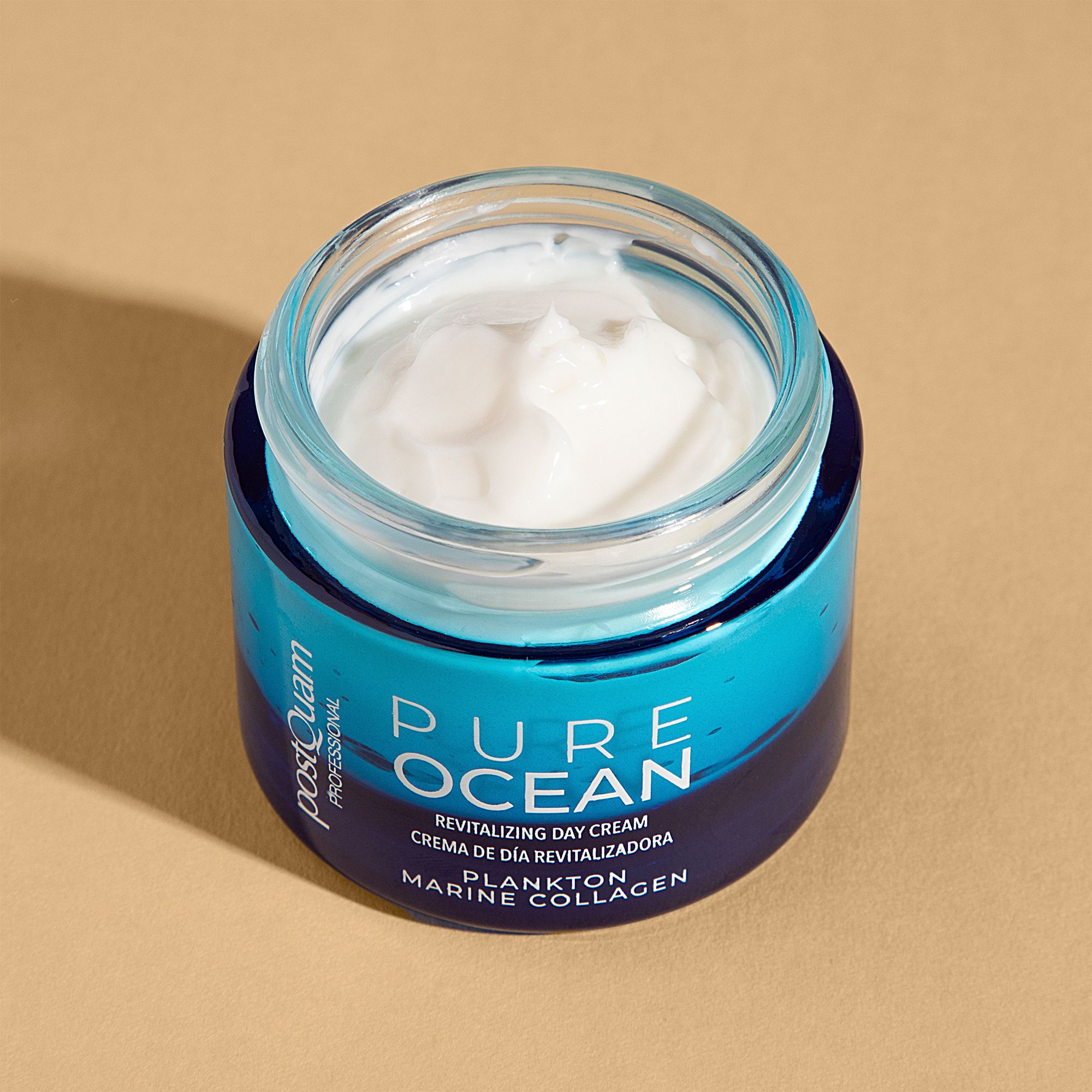 Open blauwe crèmepot met witte crème. Opschrift: PURE OCEAN, Revitalizing Day Cream, Plankton Marine Collagen. Merk: Postquam.