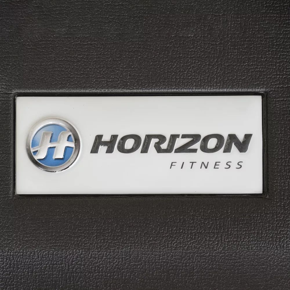Gros plan du logo Horizon Fitness sur fond noir. Panneau blanc avec logo bleu et texte.