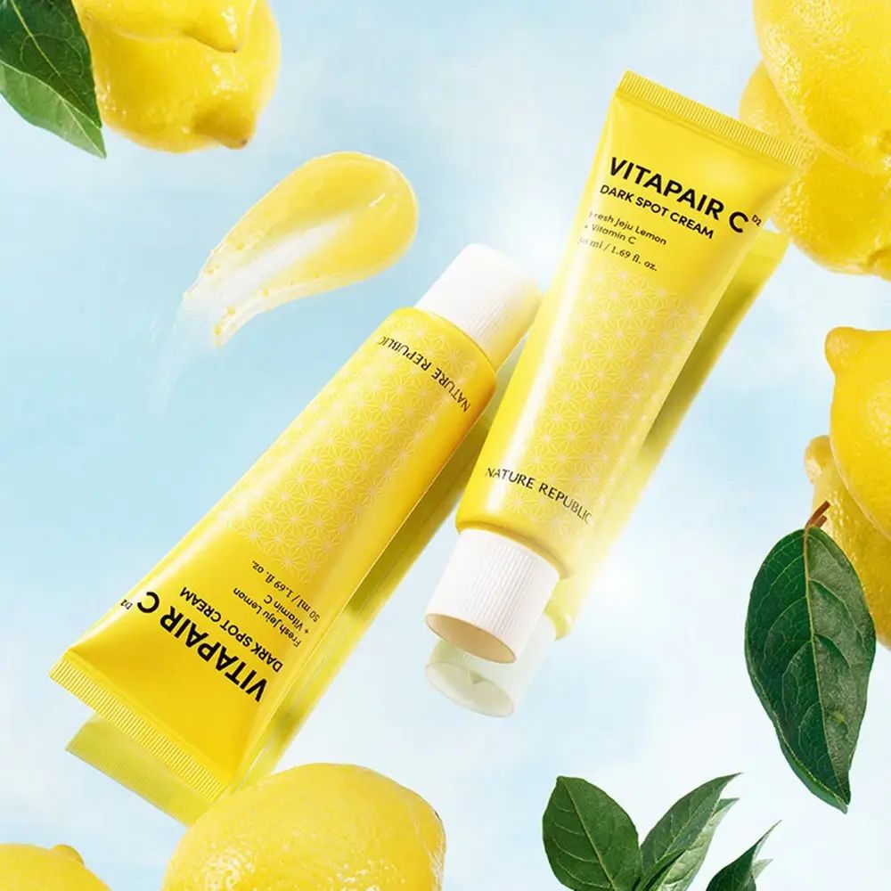 Twee gele tubes met witte dop. Opschrift: Vitapair C Dark Spot Cream. Citroenen en bladeren op de achtergrond.
