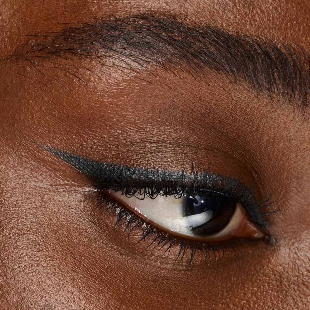 Gros plan sur un œil avec un trait de khôl noir. Le trait est tracé avec précision.