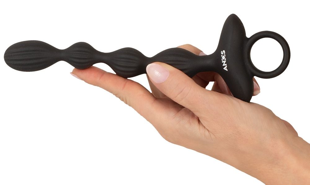 Hand houdt een zwarte, geribbelde vibrator met ring en ANOS-logo vast.
