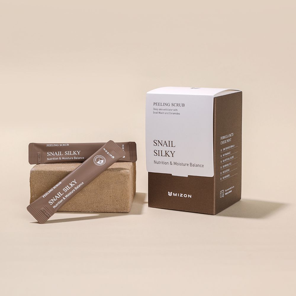 Verpakking en individuele verpakkingen op een blok. Opschrift: PEELING SCRUB, Snail Silky, MIZON. Bruine en witte kleuren.