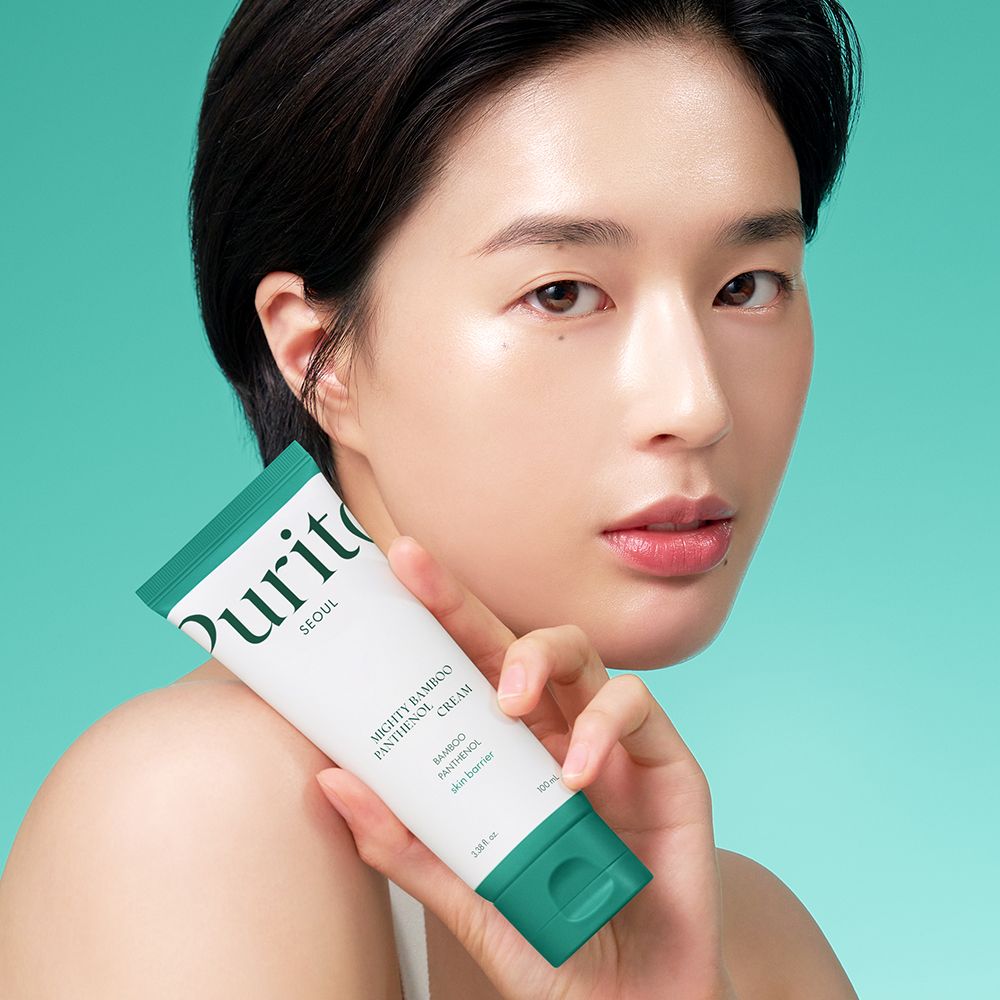 Une femme tient un tube de Purito Mighty Bamboo Panthenol Cream.