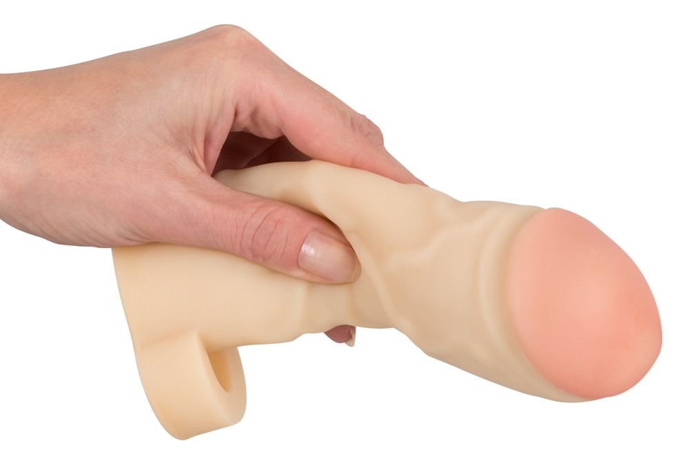 Extension de pénis beige avec extrémité rose, tenue dans une main. Surface texturée.