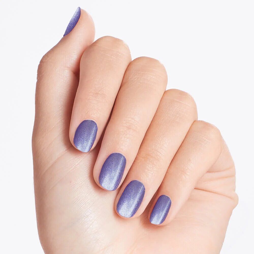 Main avec ongles vernis en violet. Le vernis à ongles a des paillettes.