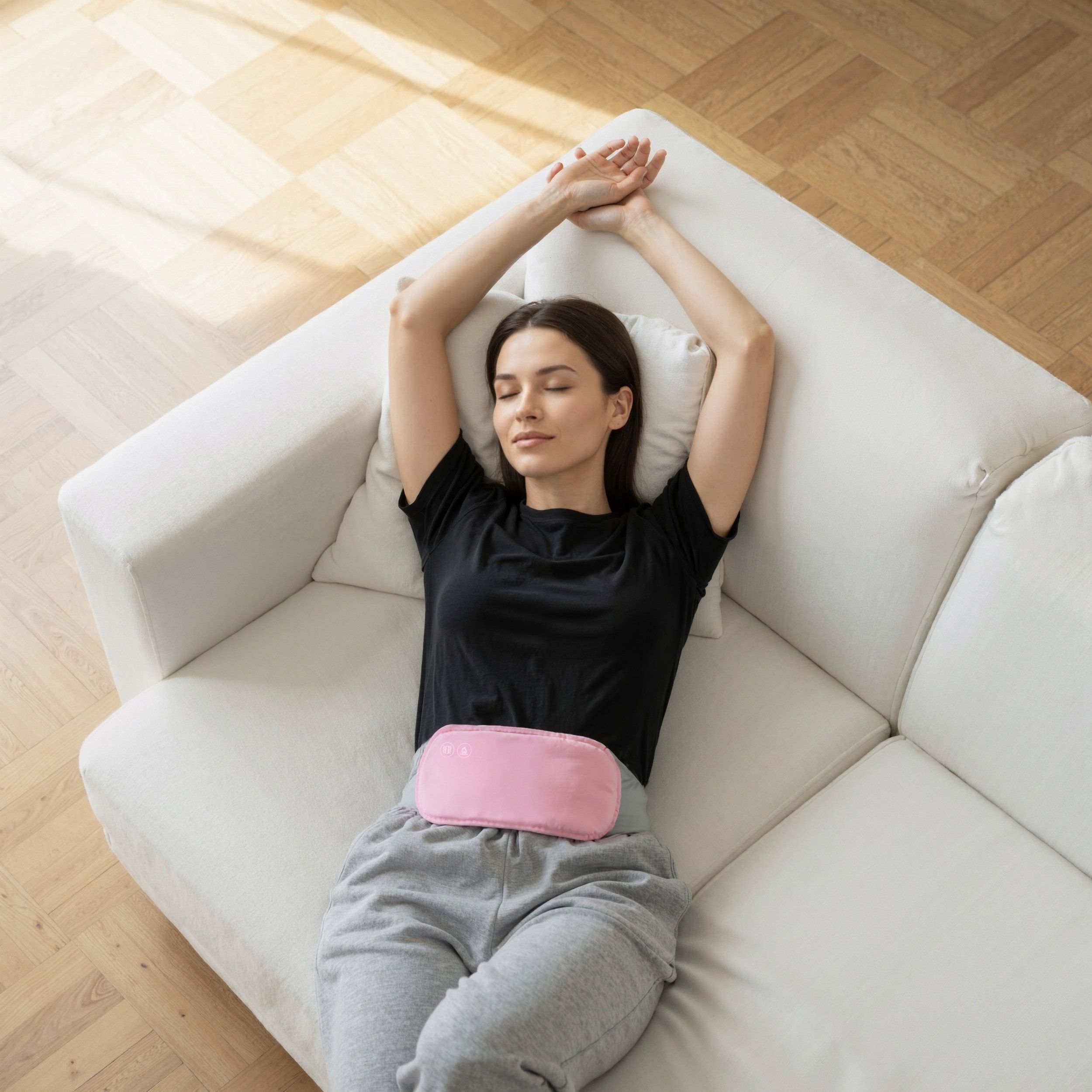 Femme allongée sur un canapé, portant une ceinture abdominale rose. La ceinture est sur le ventre. Bras au-dessus de la tête.