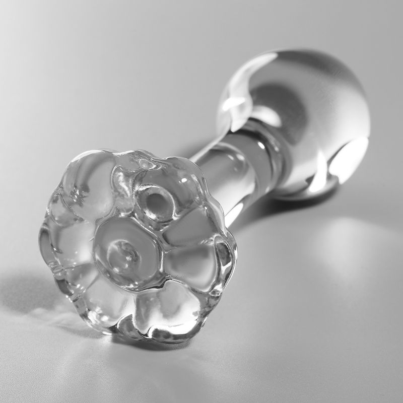 Plug anal en verre transparent, posé, avec une base détaillée en forme de fleur.
