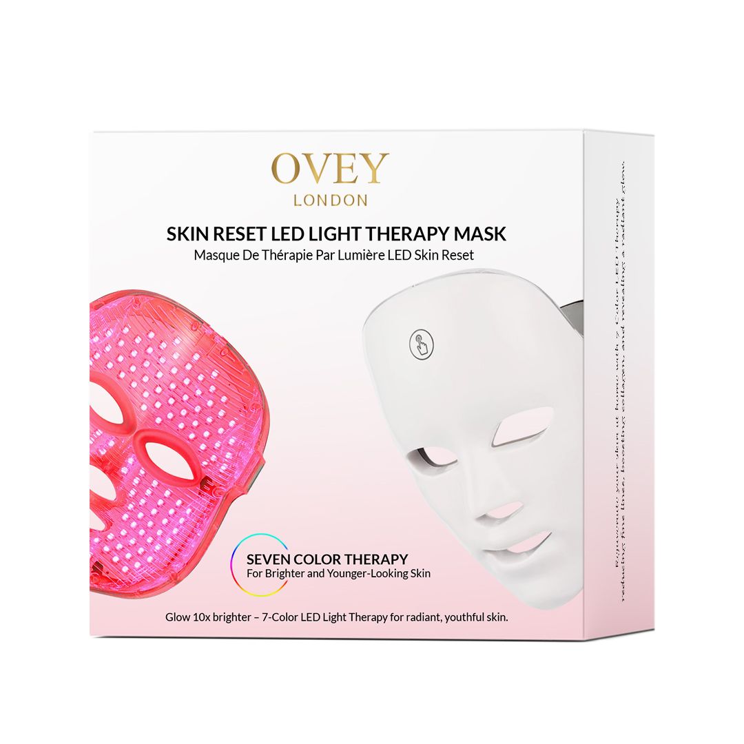 Productverpakking met een wit LED-gezichtsmasker. Tekst: SKIN RESET LED LIGHT THERAPY MASK. Zeven kleuren.