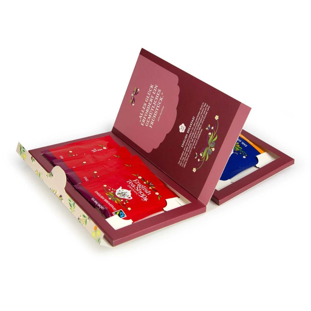 Open theedoos met theezakjes. Rode zakjes met opschrift English Tea Shop. Binnenkant met tekst.