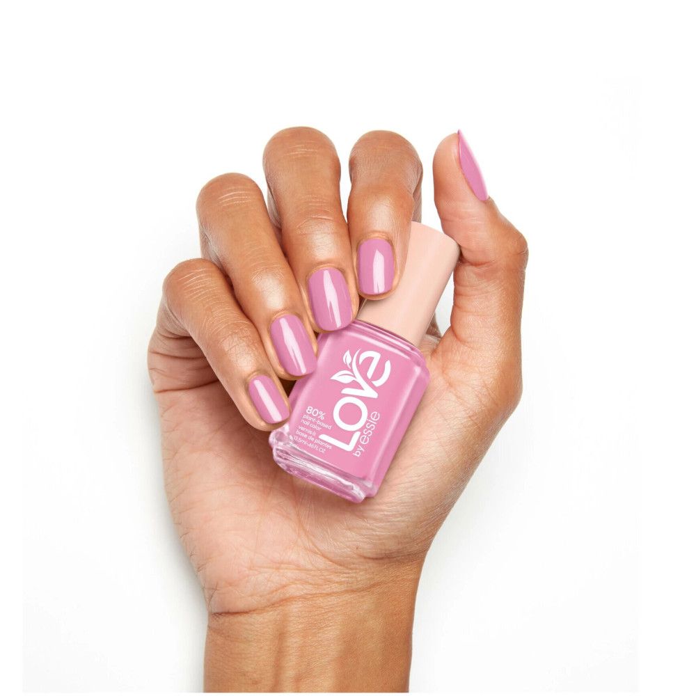 Hand met gelakte nagels en nagellakflesje. Roze nagellak van Essie.