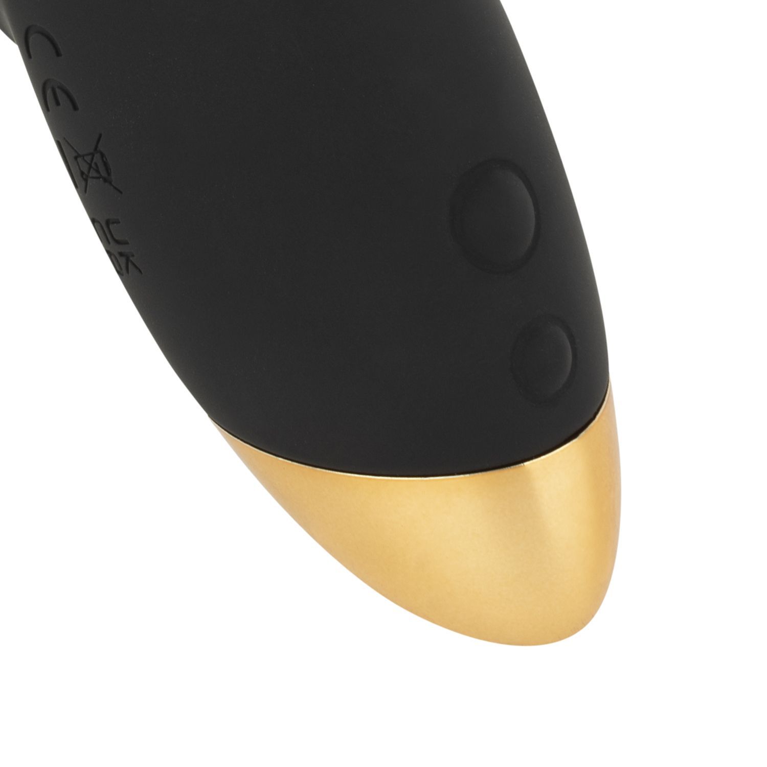Gros plan de l'extrémité du vibrateur. Boîtier noir avec deux boutons et extrémité dorée. Sur fond blanc.