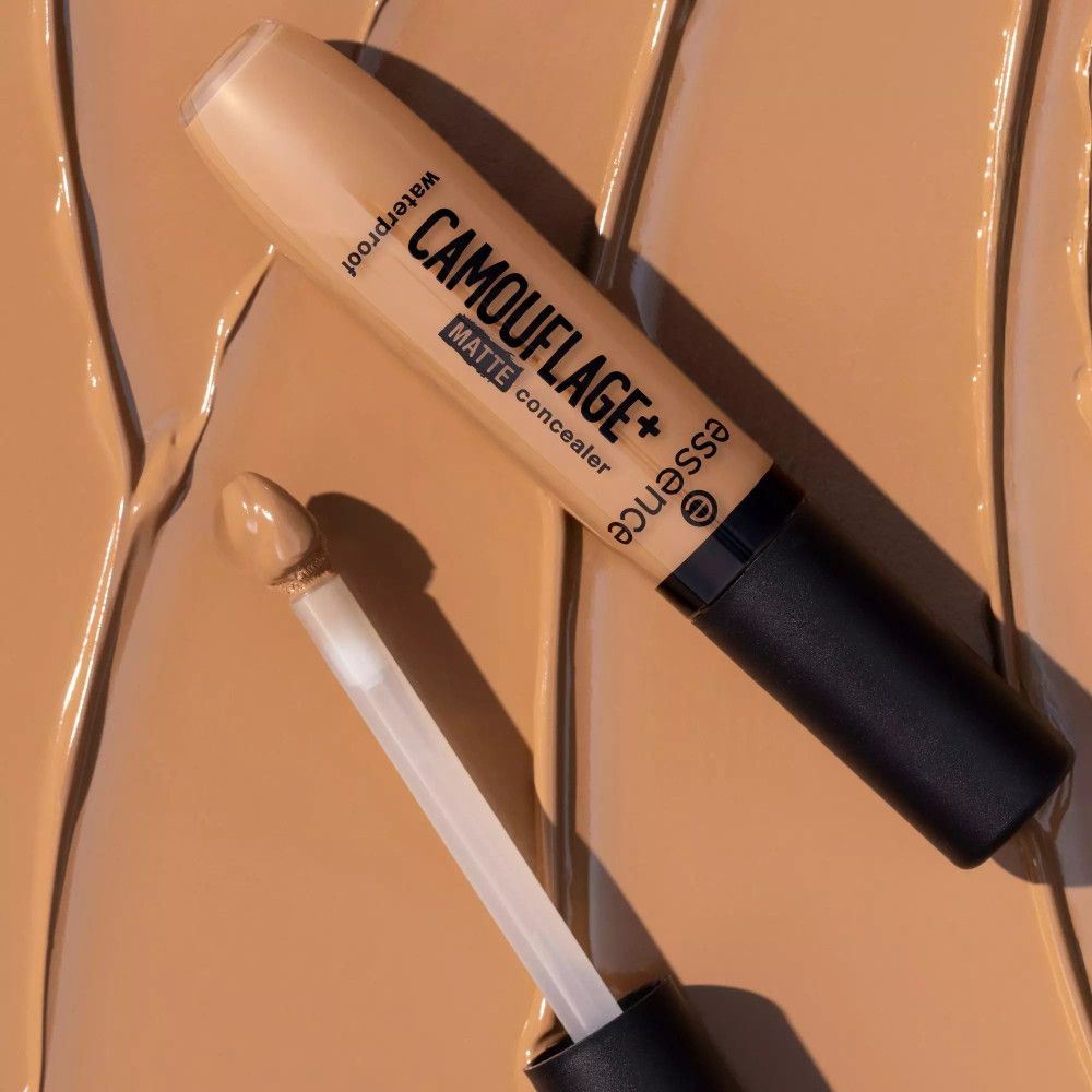 Tube de correcteur avec applicateur sur une tache de correcteur. Inscription: CAMOUFLAGE+ matte concealer, waterproof. Marque: essence.
