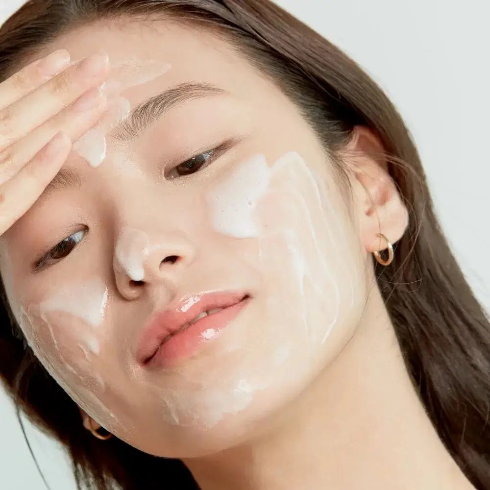 Gezicht van een persoon bedekt met schuim. Persoon raakt gezicht aan. Geen productnaam zichtbaar.