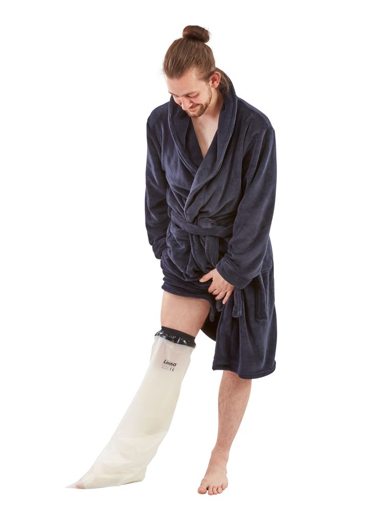 Protection de douche pour jambe, transparente, sur une personne. Bord noir, nom Limbo. Personne en peignoir.