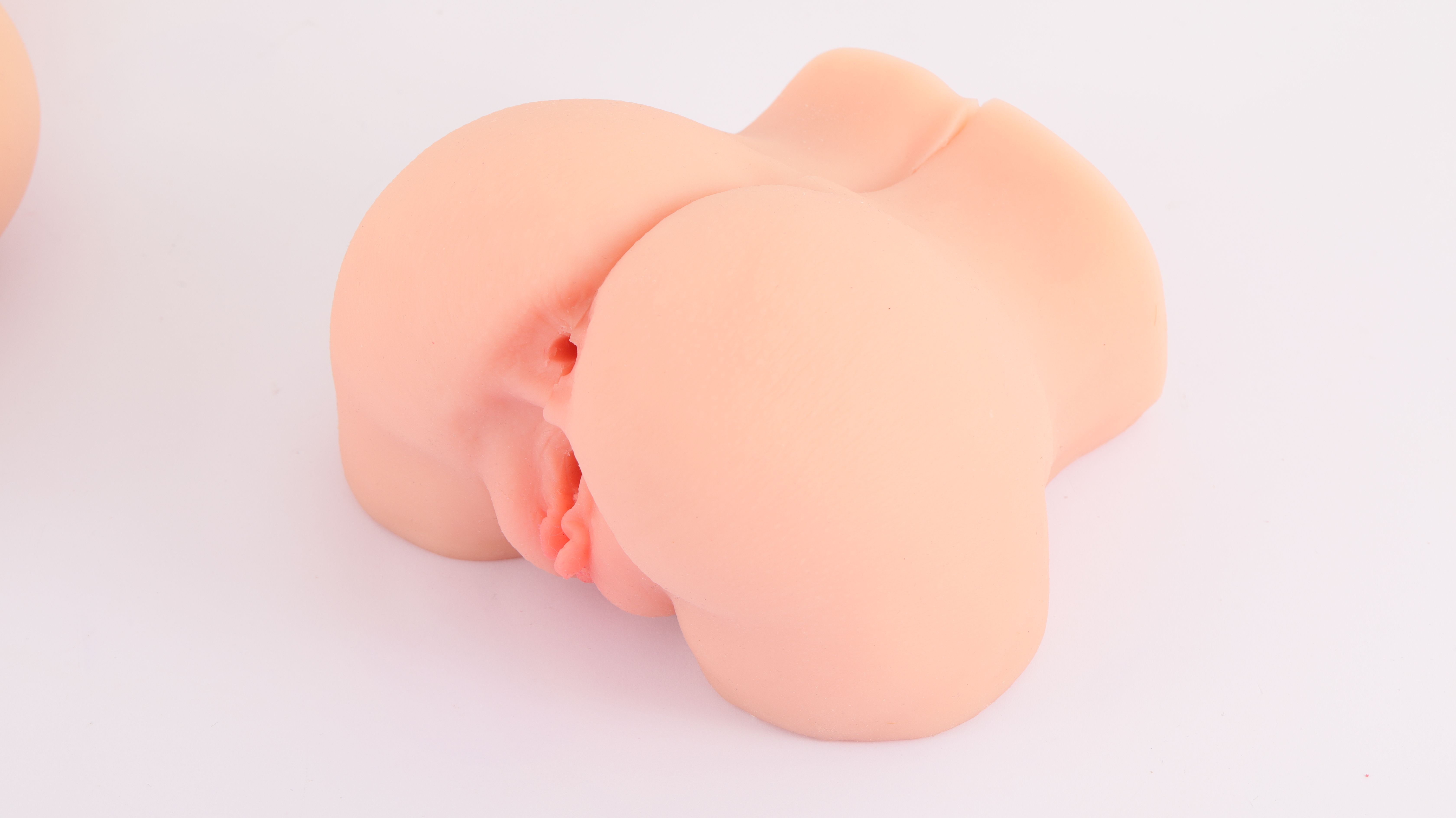 Roze, anatomisch gevormd product. Zachte, afgeronde vorm met zichtbare details. Op witte achtergrond.