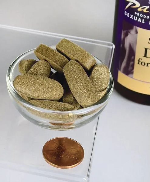 Comprimés bruns dans un bol en verre. À côté, une pièce de monnaie et un flacon étiqueté.