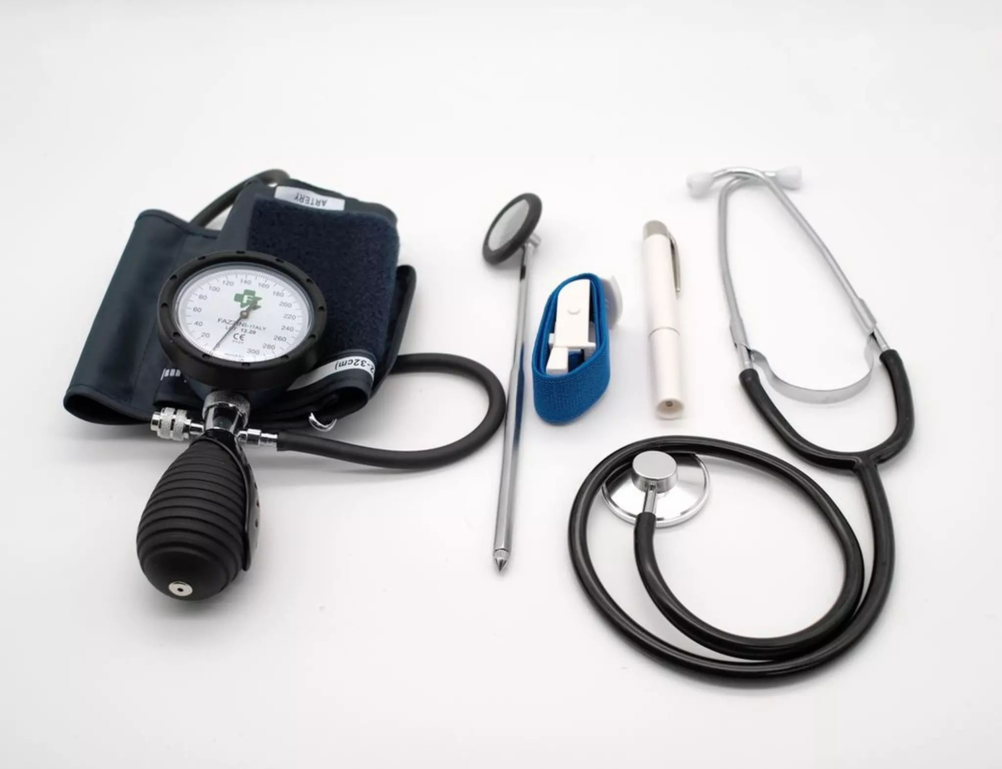 Set médical avec stéthoscope, marteau réflexe, lampe pupillaire et tensiomètre. Sur fond blanc.