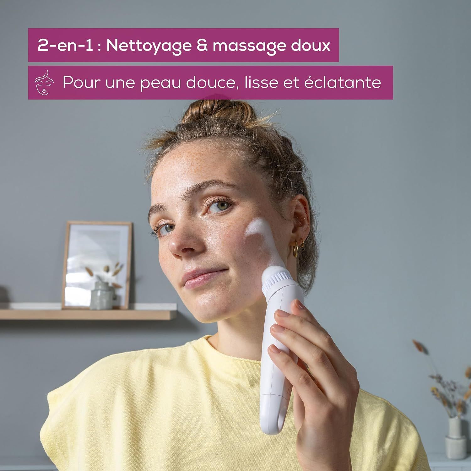 Femme aux taches de rousseur nettoyant son visage avec une brosse blanche.