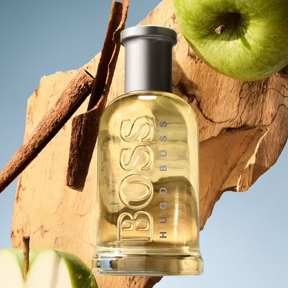 Flacon Boss Bottled Eau de Toilette. Flacon sur bois, avec pommes et bâton de cannelle. Bouchon argenté.