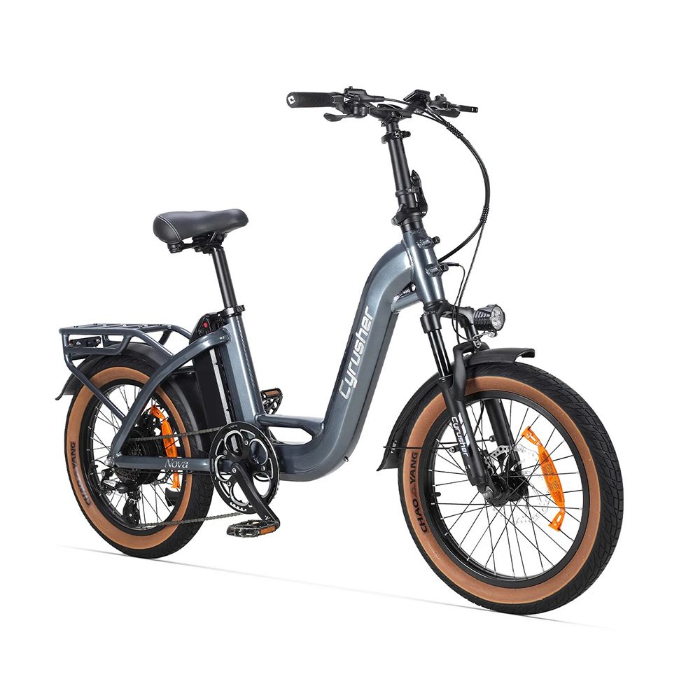 Vélo électrique gris avec pneus marron. Porte-bagages, phare et logo CYRUSHER visibles.