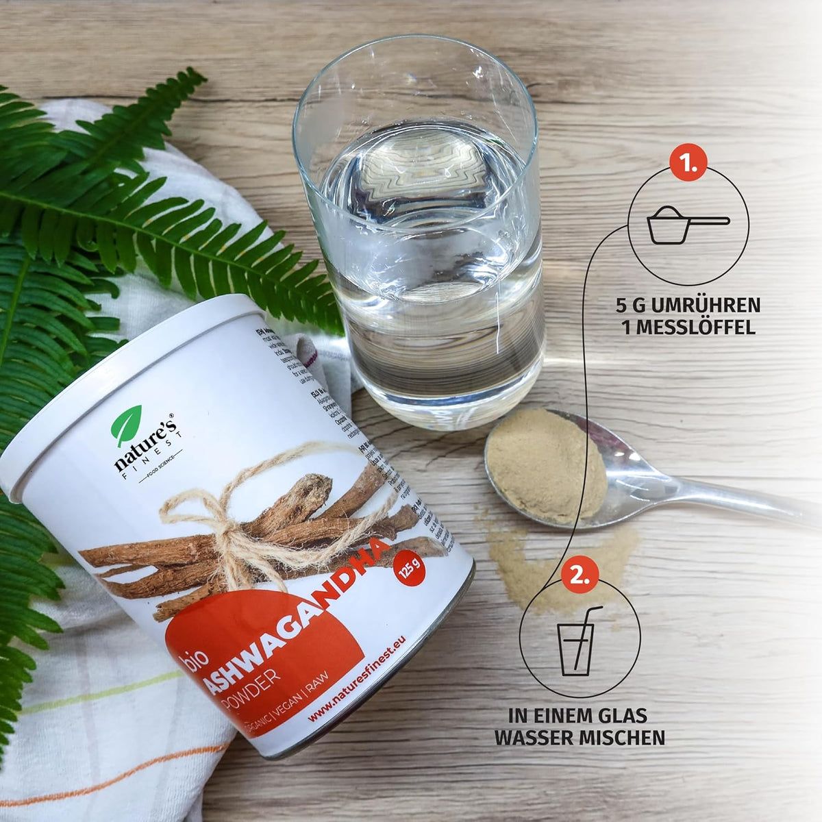 Potje bio Ashwagandha poeder, glas water, lepel met poeder. Opschrift Nature's Finest. Instructies.
