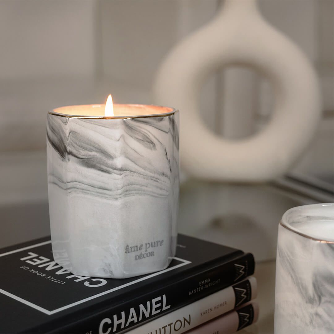 Brandende geurkaars in marmeren design houder op boeken.