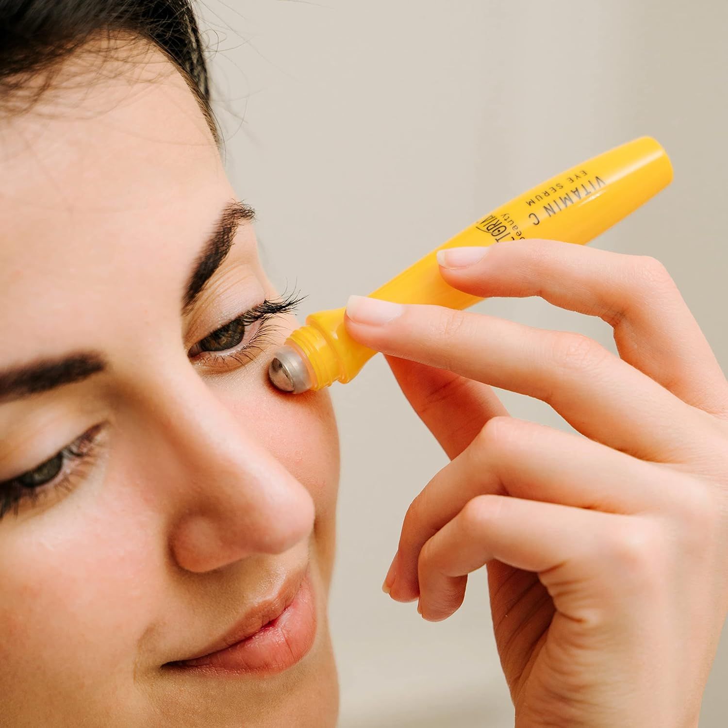 Vrouw brengt gele oogroller aan. Product wordt op het oog aangebracht. Close-up.
