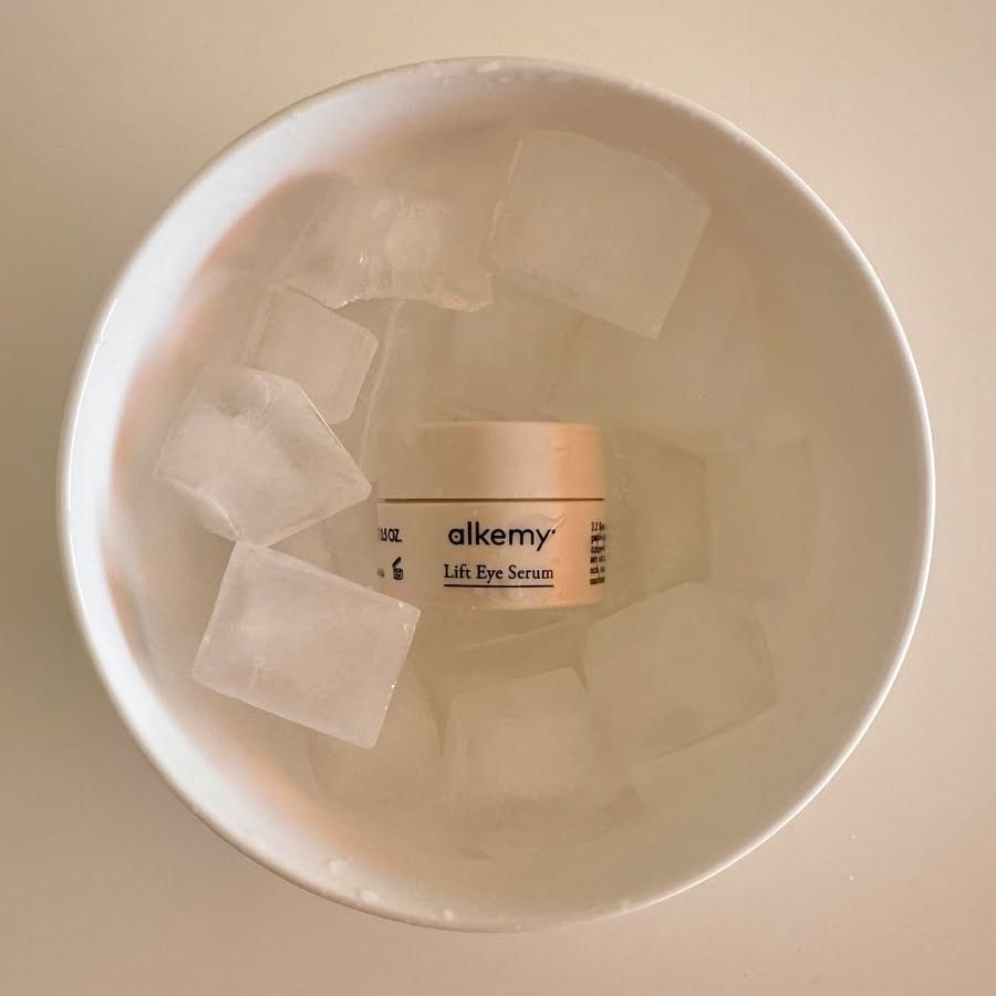 Alkemy Lift Eye Serum potje in een kom met ijsblokjes.