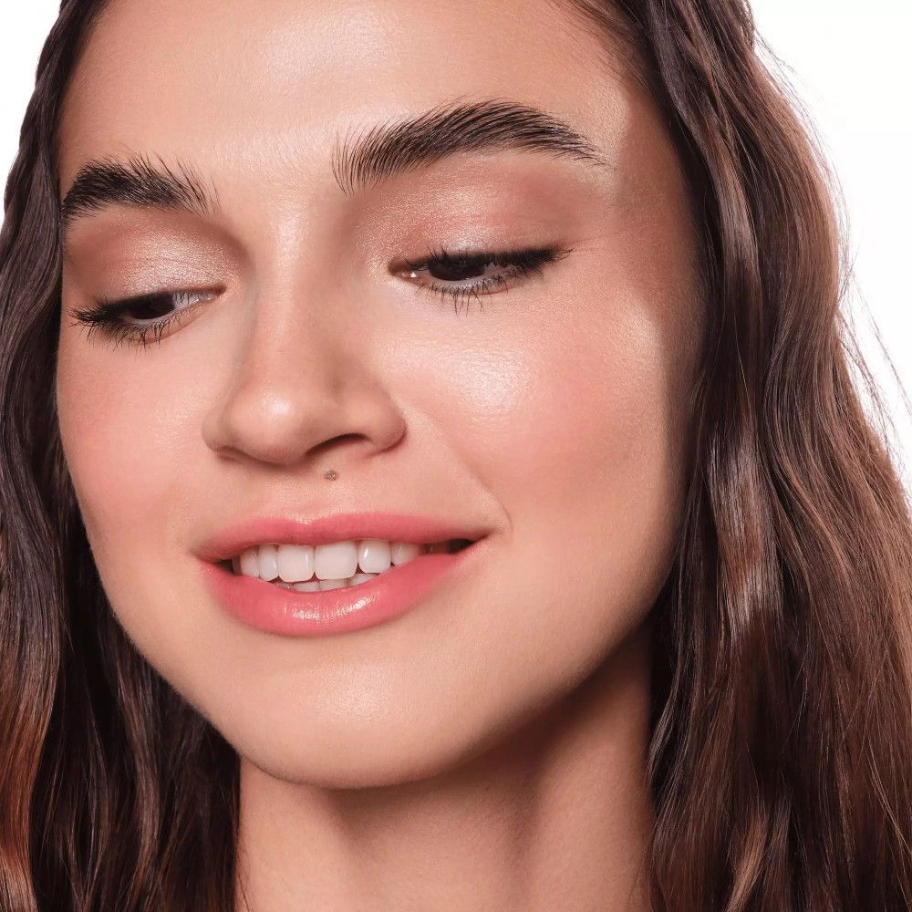 Gros plan d'une femme avec du fard à paupières crème sur les paupières. Elle regarde vers le bas. Le fard est clair et subtil.