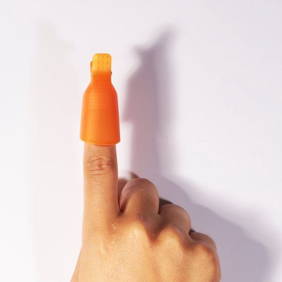 Een oranje clip op een vinger. De clip bedekt de nagel. Witte achtergrond.