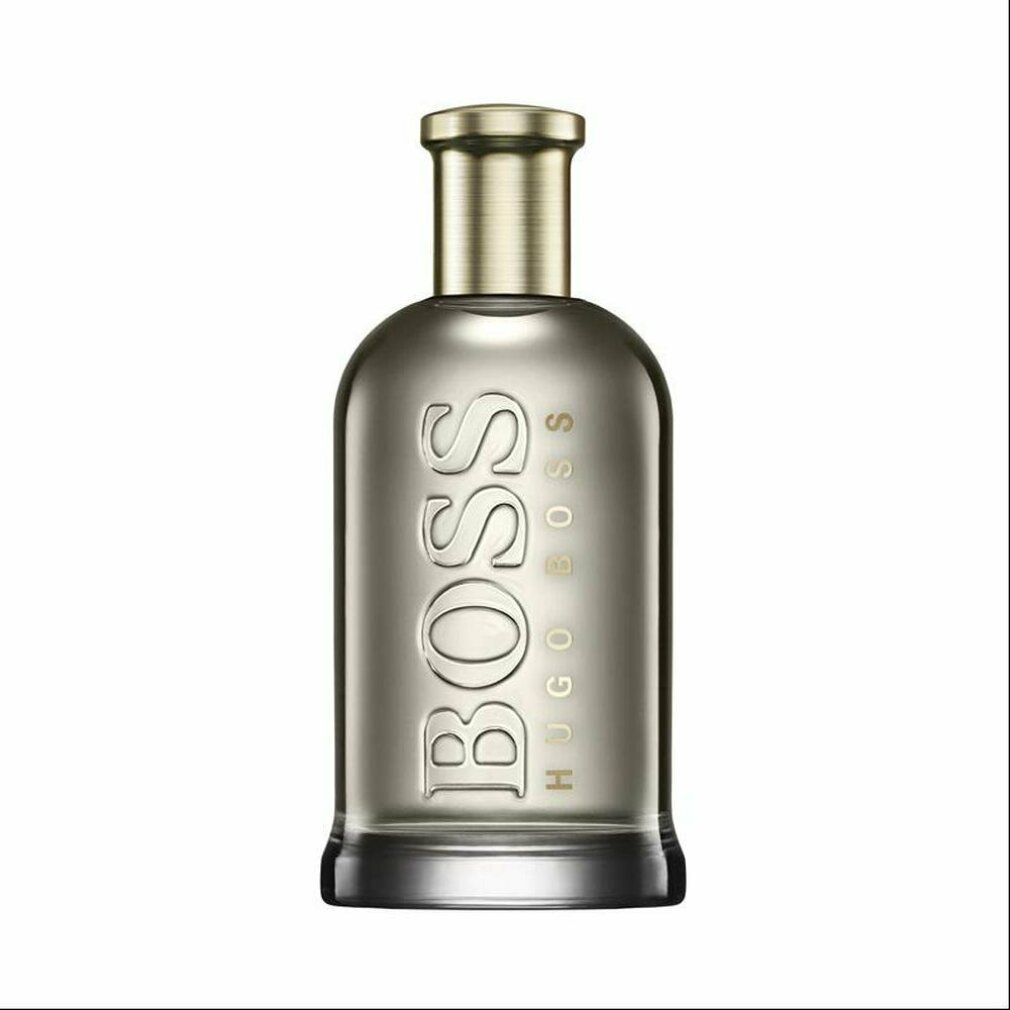 Parfumfles met gouden dop. Opschrift BOSS. Glazen fles met licht donkere vloeistof.