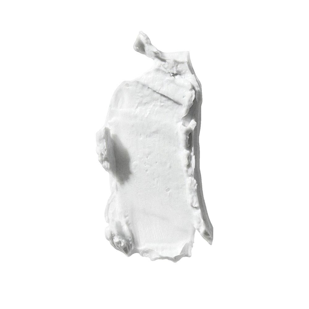 Tache blanche de pâte capillaire sur fond blanc. Texture visible.