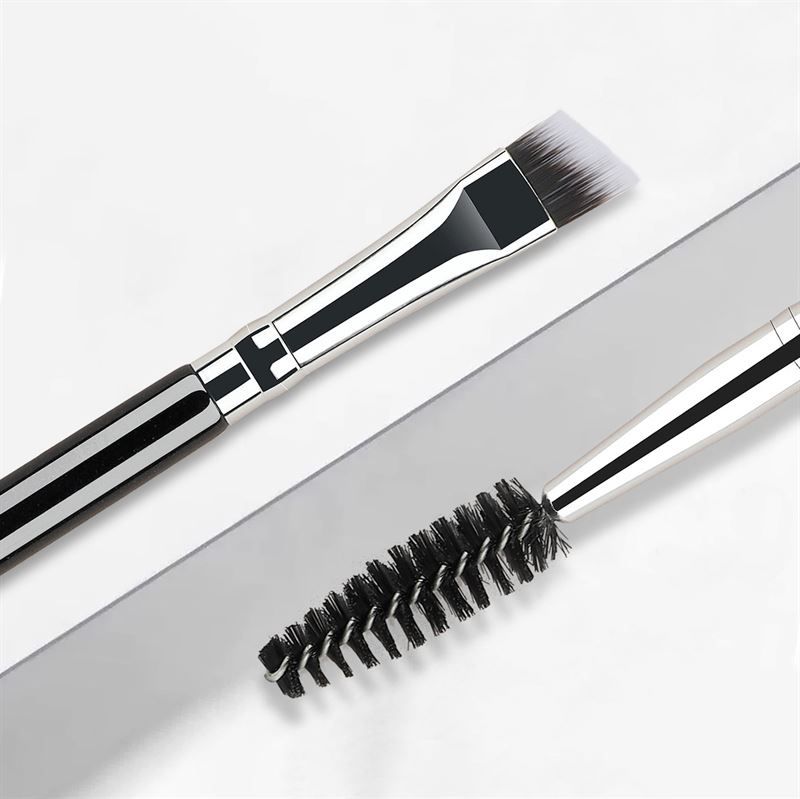Brosse à sourcils double. Une extrémité avec pinceau biseauté, l'autre avec poils en spirale. Éléments noirs et argentés.
