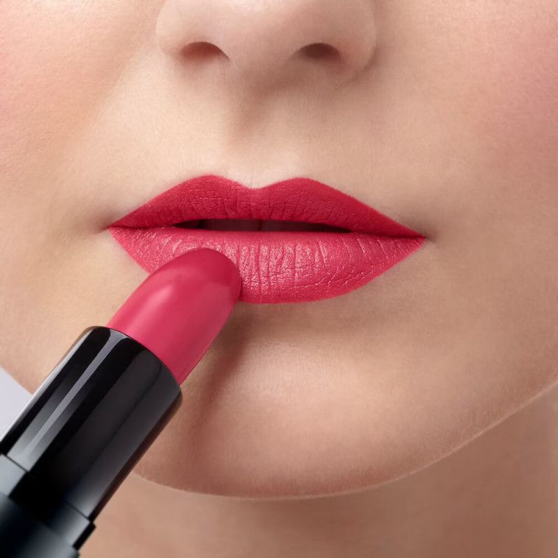 Close-up van lippen waarop rode lippenstift wordt aangebracht.