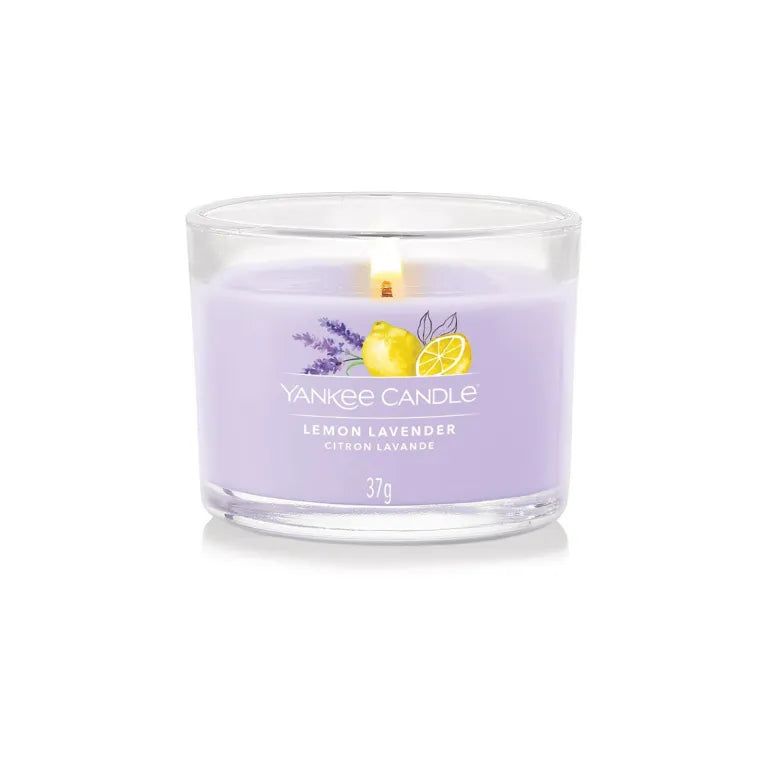 Bougie parfumée en verre. Cire lilas avec impression citron et lavande. Inscription: Lemon Lavender, Citron Lavande, 37g. Flamme allumée.