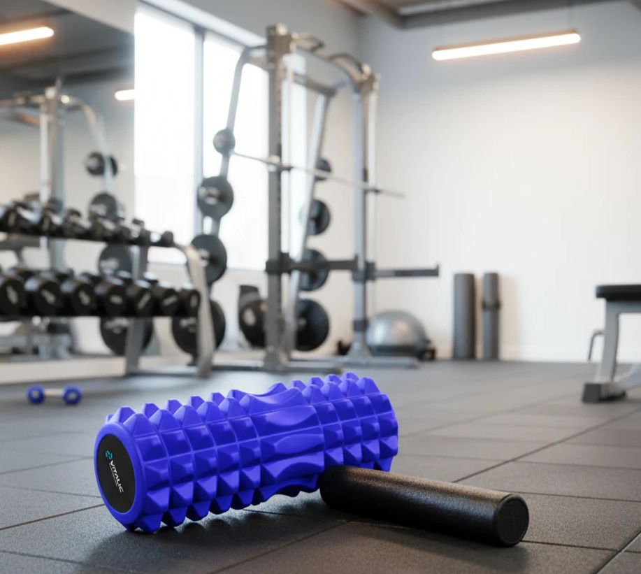Rouleau de massage bleu et mini-rouleau noir au sol dans une salle de sport. Logo VITALIC sur le rouleau.