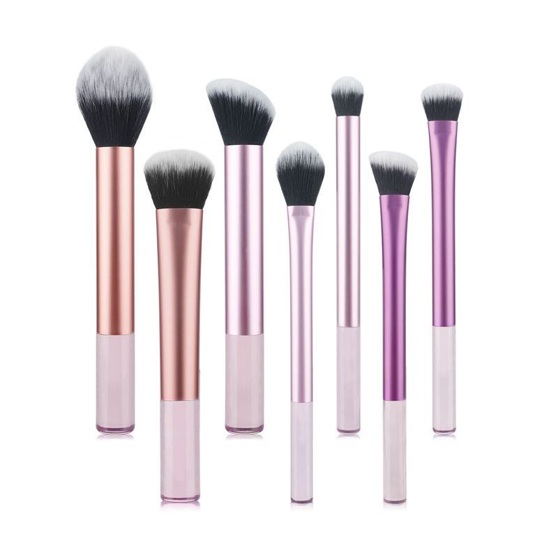 Zeven make-up borstels met zwarte haren en roze, paarse en zilveren handvatten. Verschillende vormen en maten.