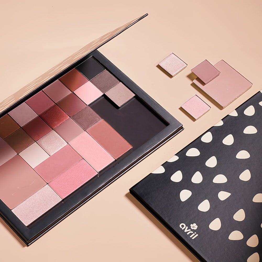 Palette de maquillage ouverte avec diverses couleurs de fard à paupières et de fard à joues dans des tons roses et bruns. Quelques fards individuels sont placés à côté.