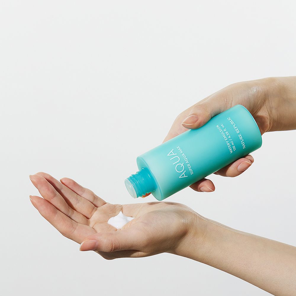 Mains tenant une bouteille turquoise. Le produit est versé dans la paume. Émulsion blanche.