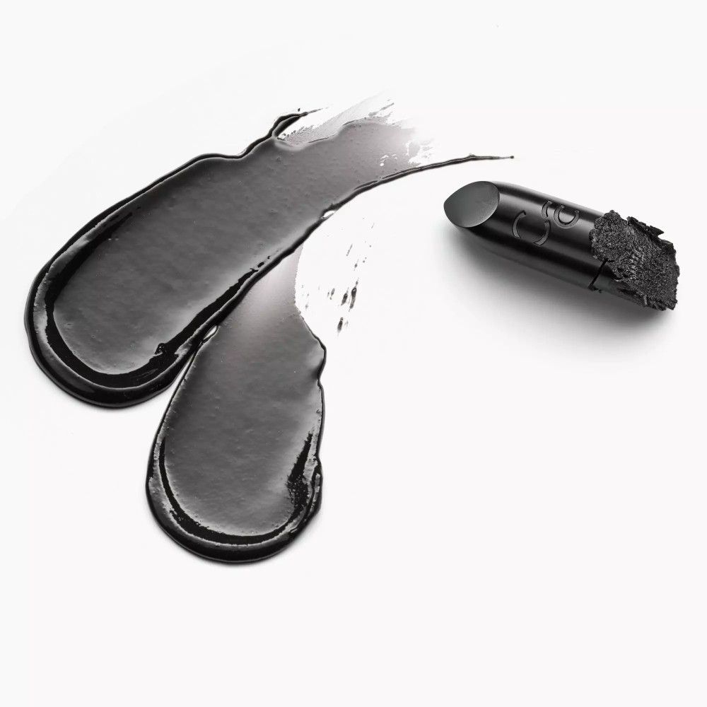 Zwarte lippenstifttextuur op witte achtergrond. Daarnaast een lippenstift. Merk: Catrice.